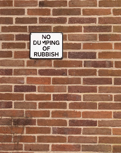 A black wheelie bin labeled 'St. John's' positioned on the edge of a quiet street at night, with its lid open and filled with assorted rubbish including white and brown paper bags and cardboard. The b